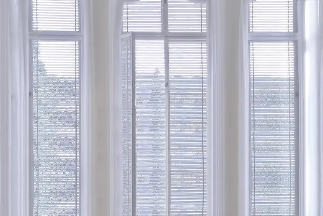 A curved ceiling-mounted curtain track following the angles of a three-facet bay window with light linen curtains.