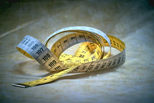 A soft measuring tape coiled on neutral cloth, ready for taking measurements.