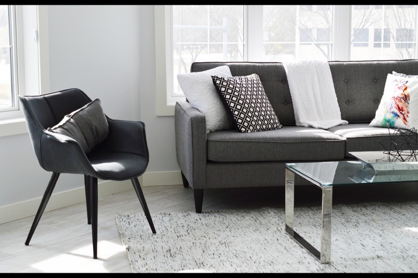 A round natural wool rug centred under a circular dining table with four chairs on its edge.