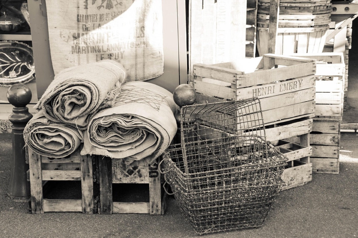 A rolled wool rug wrapped in a pale cotton sheet, standing upright in a dry storage room.