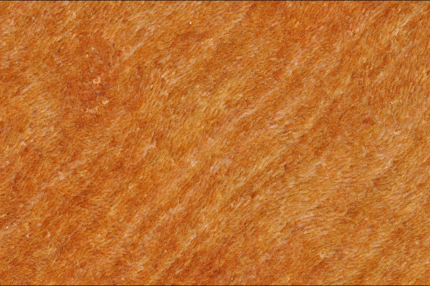 A close overhead view of a dark wool rug surface where individual fibres and light surface fuzz are visible.